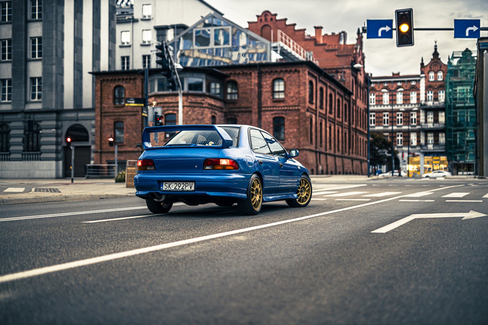 Niebieska Impreza GC8 na skrzyżowaniu przy ceglanej kamienicy. Fot. Wowson